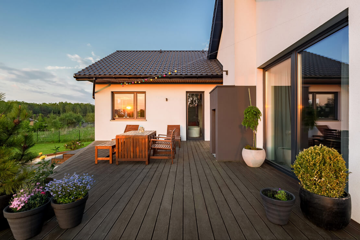 Moderne Terrassengestaltung trendige Einrichtungsideen Holzterrasse Sitzecke viele Topfpflanzen schöner Blick