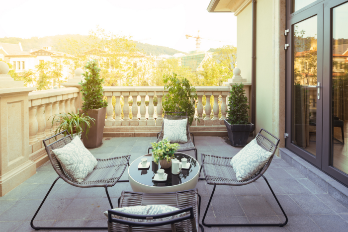 Moderne Terrassengestaltung trendige Einrichtungsideen Sitzecke Stühle aus Metall Sitzkissen runder Tisch viele Grünpflanzen schöner Blick