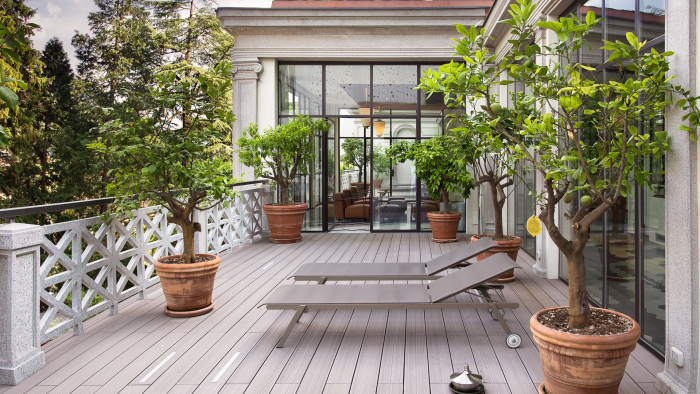 Moderne Terrassengestaltung trendige Einrichtungsideen graue Holzterrasse zwei Liegestühle Grünpflanzen in Töpfen