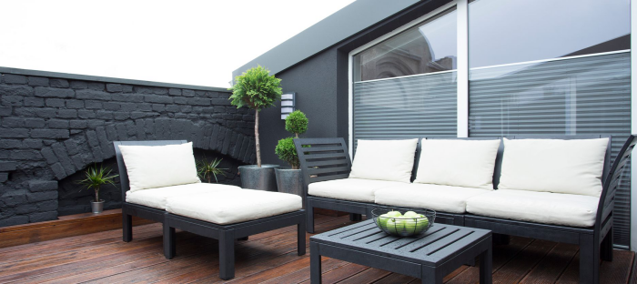 Moderne Terrassengestaltung trendige Einrichtungsideen graue Steinwand Sichtschutz moderne Outdoor Möbel weiße Polsterung Kontrast