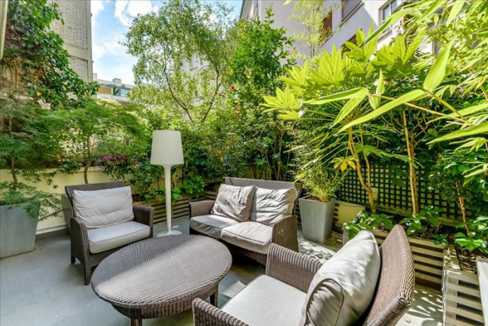 Moderne Terrassengestaltung trendige Einrichtungsideen schicke Outdoor Möbel üppiges Grün als Sichtschutz