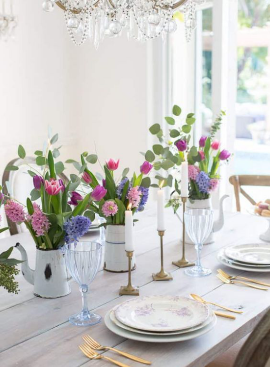 Tischdeko Frühling Esstisch aus Holz ohne Tischdecke in der Mitte alte Gießkannen mit Frühlingsblumen Tulpen Hyazinthen viel Grün zwei weiße Kerzen