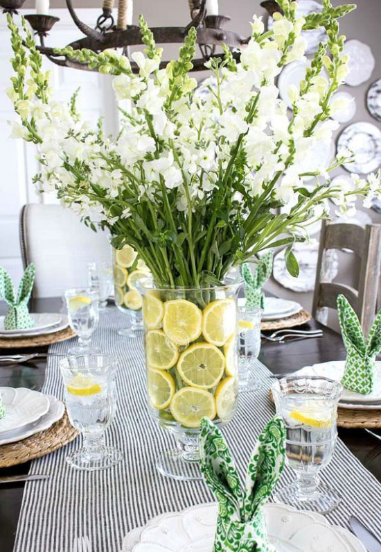 Tischdeko Frühling große Vase weiße Gladiolen Wasser mit Zitronenscheiben gestreifter Tischläufer