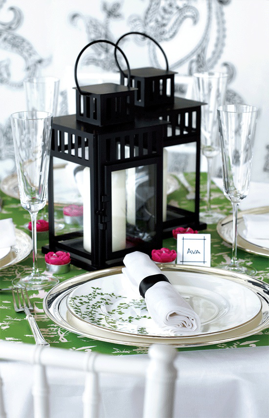 Tischdeko Frühling stilvoll gedeckter Tisch zwei schwarze Laternen weiße Kerzen weiße Serviette grüne Tischdecke kleine Kerzen in Violett