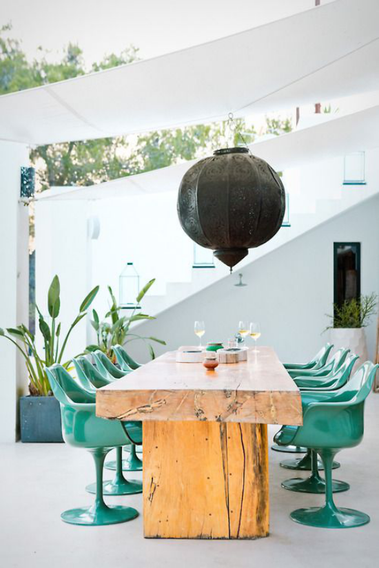 Essecke draußen hochmoderne elegante Plastikstühle Esstisch aus Holz dicke Tischplatte dunkle Hängelampe