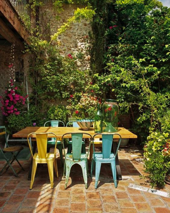 Essecke draußen in viel Grün gebettet Gartenblumen alter Holztisch Retro Stühle