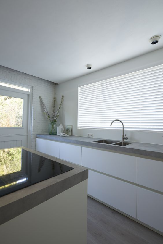 Küchenarbeitsplatten aus Beton minimalistisches Küchendesign glänzende Oberflächen Spüle Fensterrollos