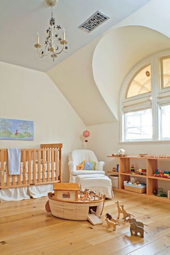 Babyzimmer mit Dachschräge gerundetes Fenster niedrige Möbel viel freier Platz Regal Spielsachen weißer Sessel in der Ecke