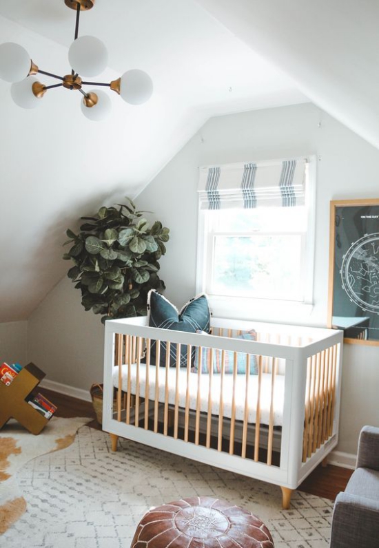 Babyzimmer mit Dachschräge viel Licht Bett vor dem Fenster Fensterrollos Grünpflanze im Topf