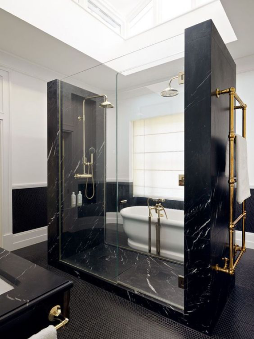 Marmor im Bad auffälliges Baddesign schwarzer Marmor Dusche weiße Badewanne goldglänzende Armatur viel Tageslicht Dachfenster