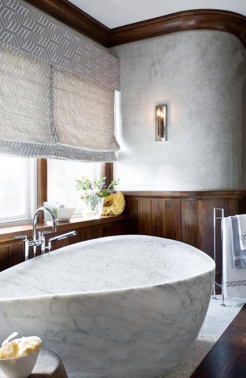 Marmor im Bad runde Badewanne aus hellgrauem Marmor Holzvertäfelung großes Fenster viel Tageslicht