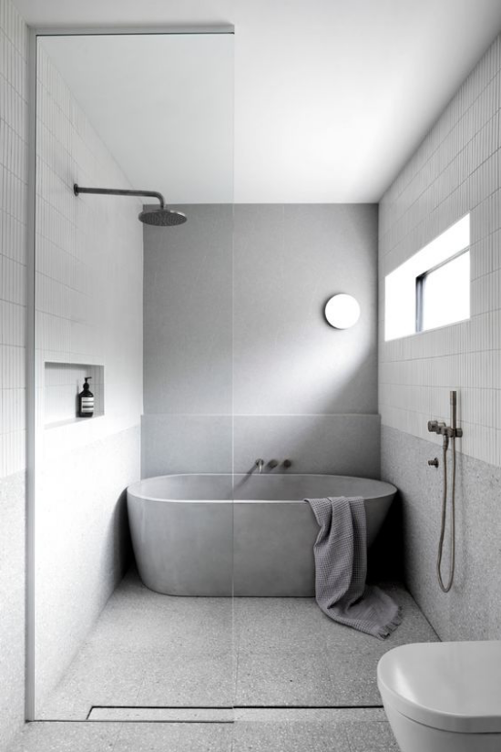 Moderne Badezimmer im minimalistischen Stil Badewanne getrennt durch Glaswand WC kleines Fenster natürliches Licht