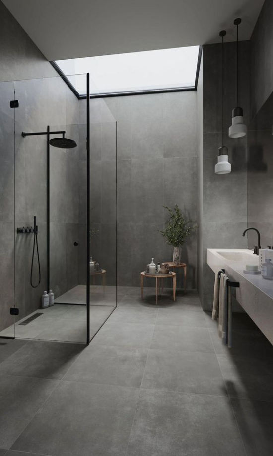 Moderne Badezimmer im minimalistischen Stil mit Industrial Style gepaart Betongrau eine grüne Pflanze frische Note Holzhocker Glaswand Dusche