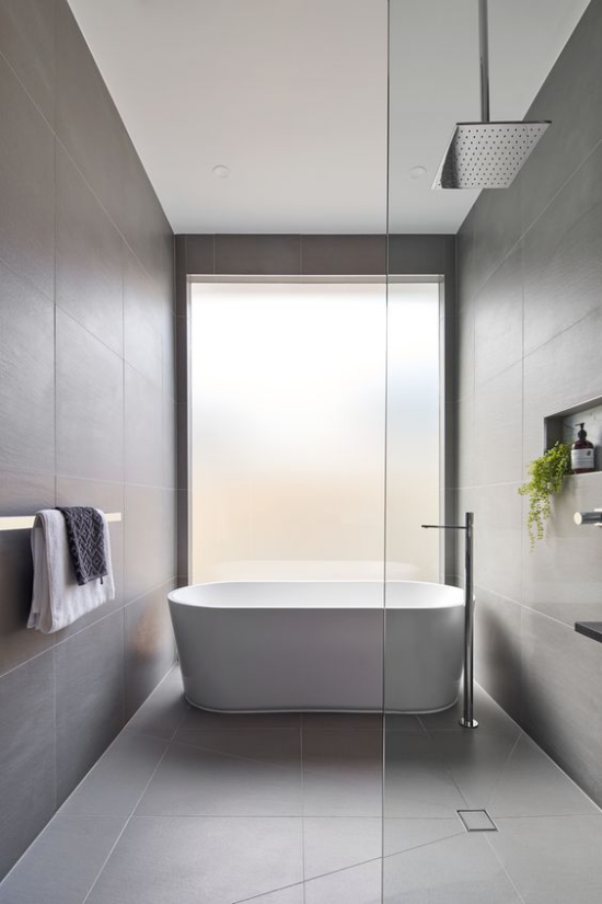 Moderne Badezimmer im minimalistischen Stil schlichtes Design gerade Linien Badewanne Glaswand eine grüne Badpflanze