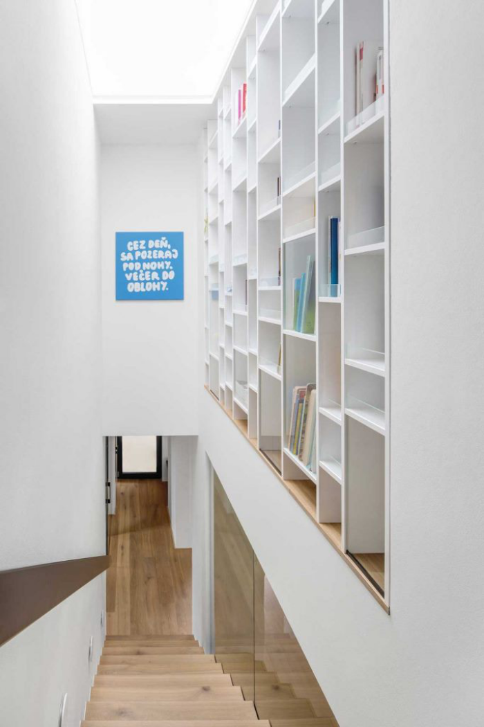 Einfamilienhaus offener Grundriss neutrale Farbpalette Treppenhaus ganz in Weiß rechte Wand mit Bücherregalen