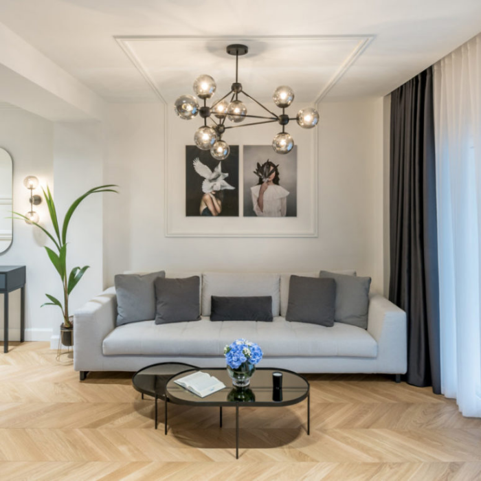 Minimalismus trifft Klassik elegante Raumgestaltung im Wohnzimmer graues Sofa grüne Topfpflanze Kaffeetisch Glasplatte Wandbilder