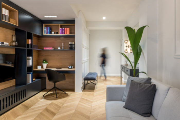 Minimalismus trifft Klassik integriertes Homeoffice im Wohnzimmer graues Sofa Holzregale mit schwarzen Fronten