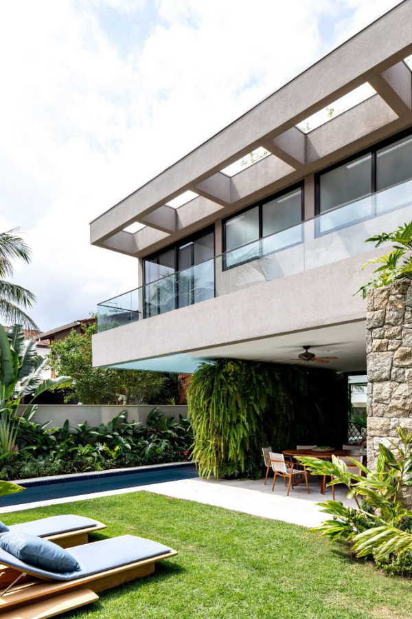modernes Haus in Brasilien mit tropischem Flair Außenaussicht Glas Beton Steinwand viel Grün Gras Gartenliegen
