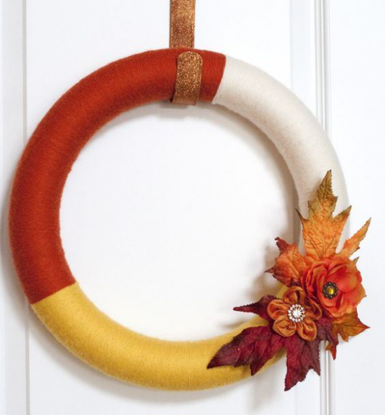 Herbstkranz aus Garn an der Haustür in drei Farben plus künstliche Herbstblätter und Blumen in den Farben des Herbstes