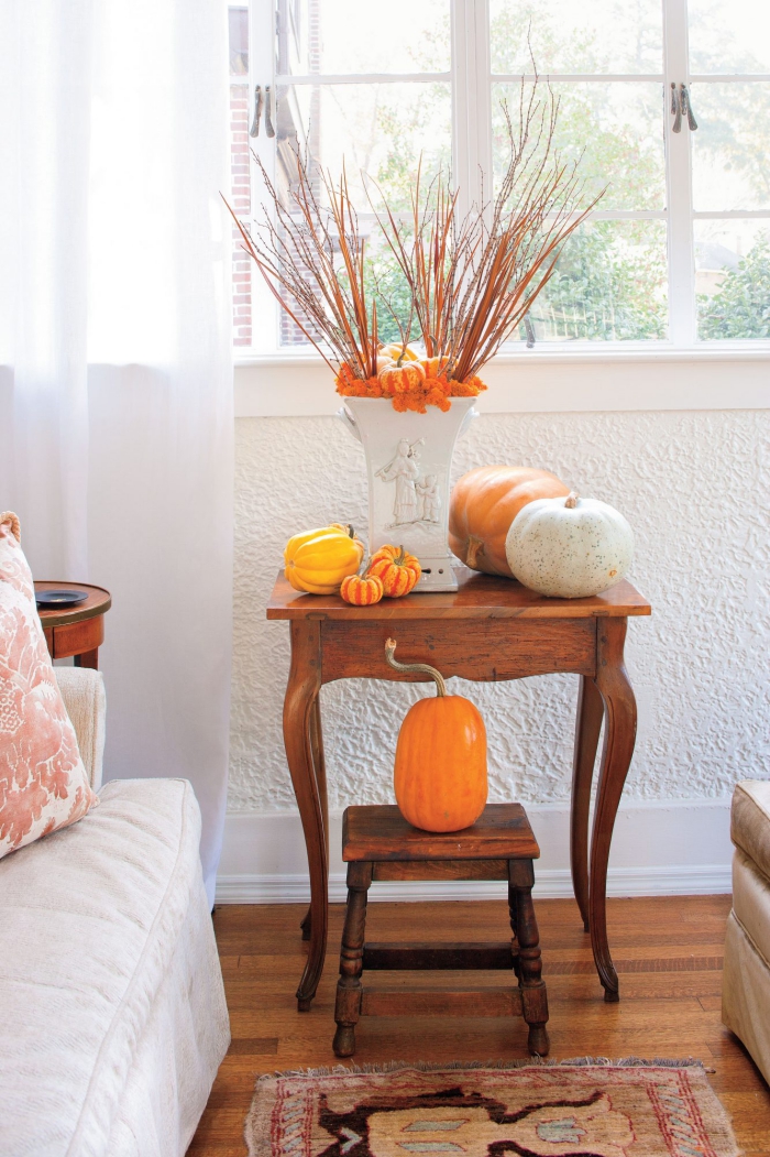 Herbstdeko kinderleichte Ideen zum Nachmachen auf einem Beistelltisch vor dem Fenster Kürbisse weiße Vase mit Herbstlaub