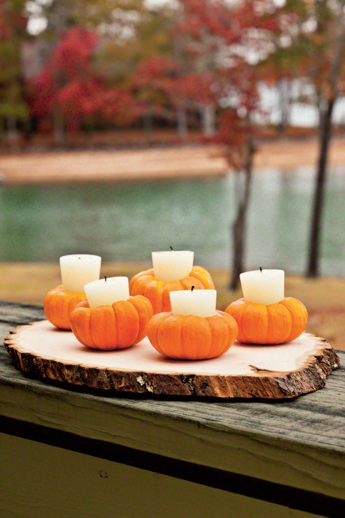 Herbstdeko kinderleichte Ideen zum Nachmachen für die Fensterbank kleine Kürbisse Teelichter weiße Kerzen auf Holzplatte