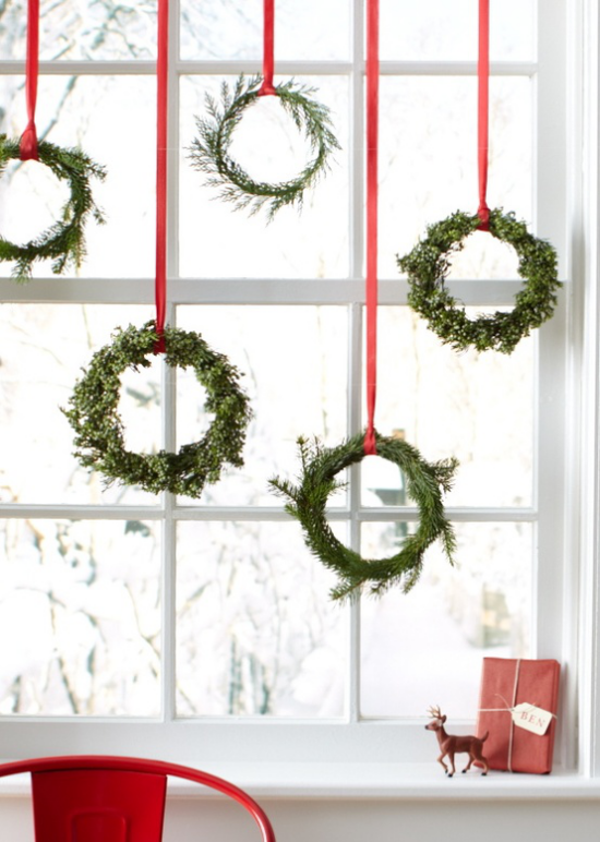 skandinavische Weihnachtsdeko Fensterdeko schöne selbstgebundene Kränze aus Tannenzweigen rote Schleifen