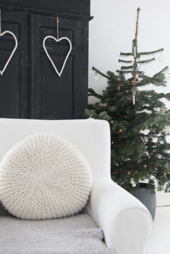 skandinavische Weihnachtsdeko je einfacher desto schöner kleiner Christbaum wenig geschmückt in der Ecke hinter weißem Sofa