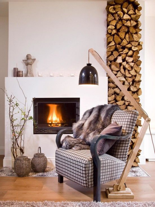 Brennholz richtig lagern Holzregal eingebautes Holzregal neben dem Kamin loderndes Feuer Sessel weiche Texturen Gemütlichkeit pur