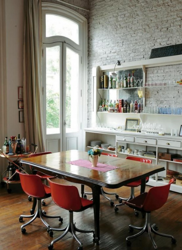 weiße Ziegelwand Esszimmer Esstisch aus Holz rote Stühle Schränke Geschirr