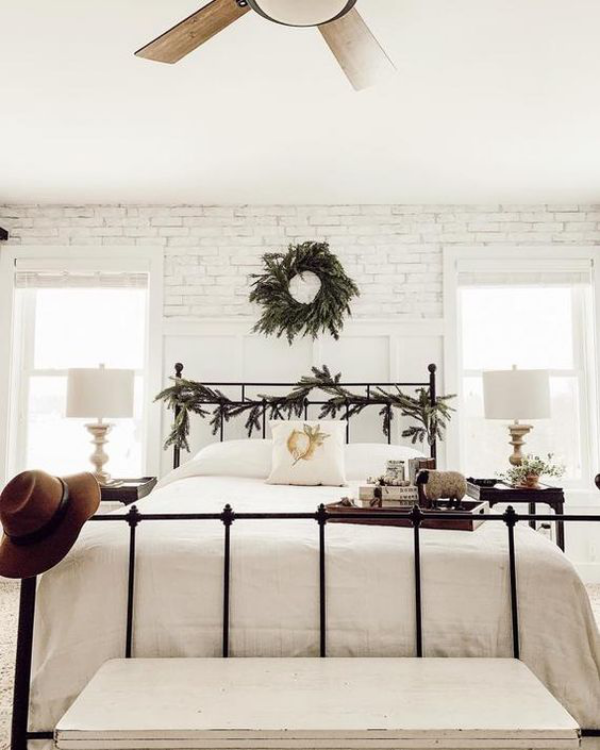 weiße Ziegelwand helles Ambiente gemütliches Schlafzimmer bequemes Bett Kranz an der Wand