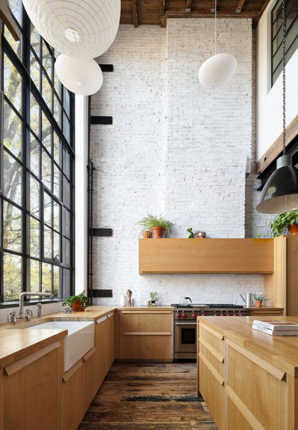 weiße Ziegelwand moderne Küche großes Fenster links Holzschränke rechts Hängeleuchten grüne Topfpflanzen
