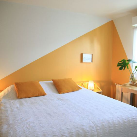 Gelbe Akzentwand im Interieur dreieckiges geometrisches Muster Schlafzimmer