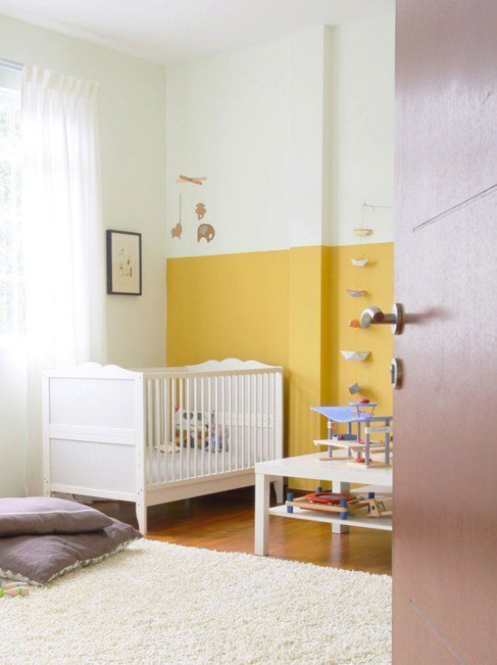 Gelbe Akzentwand im Interieur im Babyzimmer neutrales Weiß Teppich Kinderbett