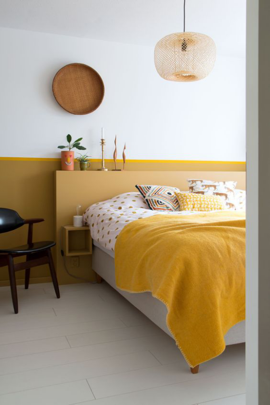 Gelbe Akzentwand im Interieur im Schlafzimmer warme Raumatmosphäre ein Teil der Wand akzentuieren gelbe Decke helles Holz