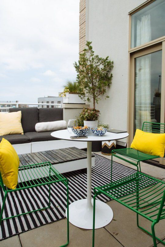 Veranda frühlingshaft gestalten gepoltertes Sofa Metallstühle runder Tisch gelbe Kissen Dachterrasse