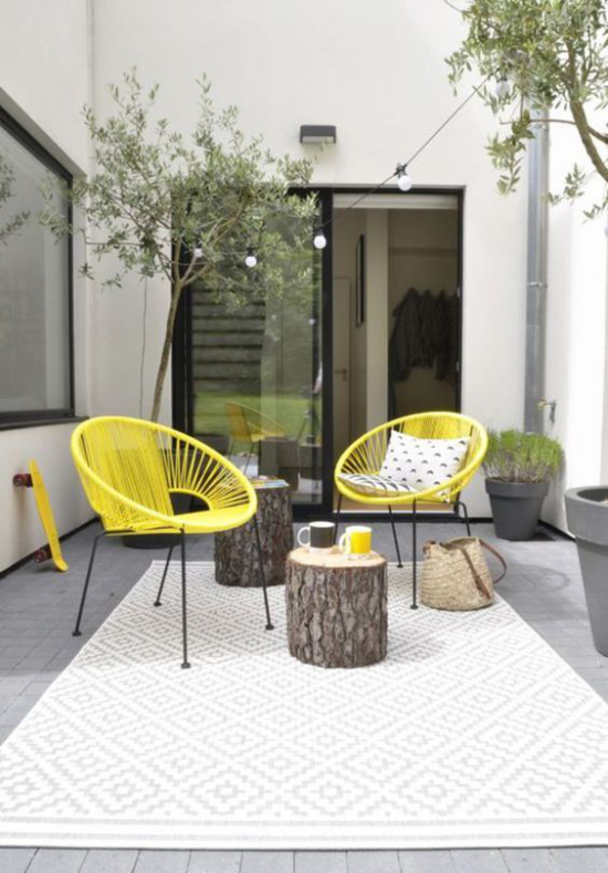 Veranda frühlingshaft gestalten zwei gelbe Stühle zwei Baumstämme einfache aber schöne Einrichtung