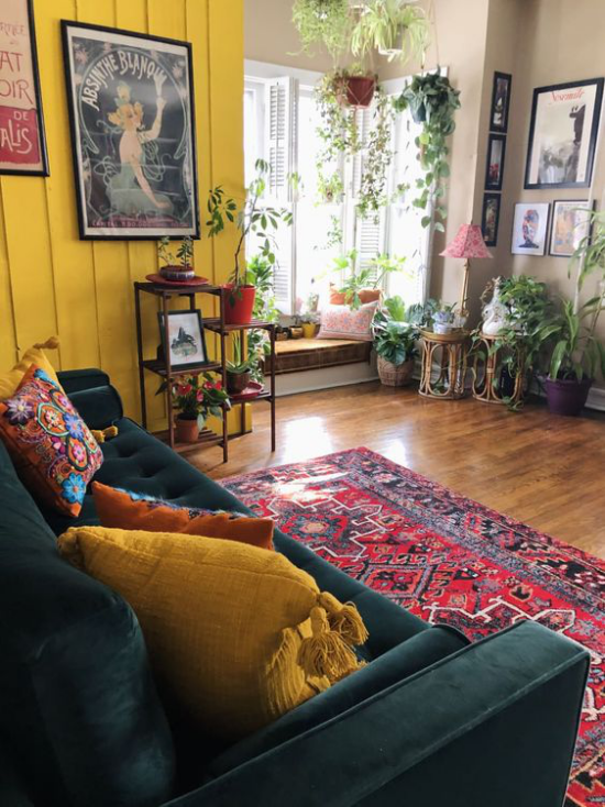 leuchtendes Gelb im Wohnzimmer bunte Wohnaccessoires Ethno Elemente zahlreiche Grünpflanzen am Fenster