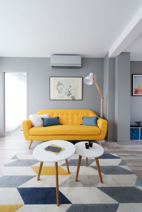 leuchtendes Gelb im Wohnzimmer minimalistischer Raum wenig Möbel gelbes Sofa viel Grau Teppich