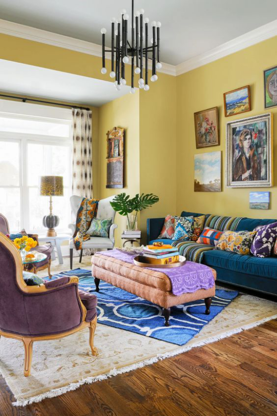 leuchtendes Gelb im Wohnzimmer viele Farben sich komplementieren Gemälde an der Wand Grünpflanzen heller Teppich orientalische Motive