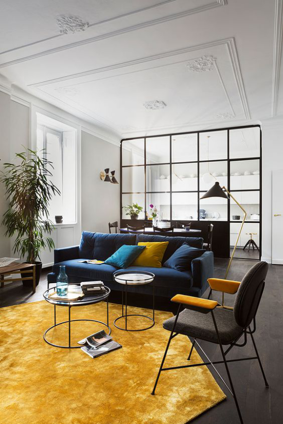 leuchtendes Gelb im Wohnzimmer weiter gemütlicher Raum gelber Teppich dunkelblaue Couch