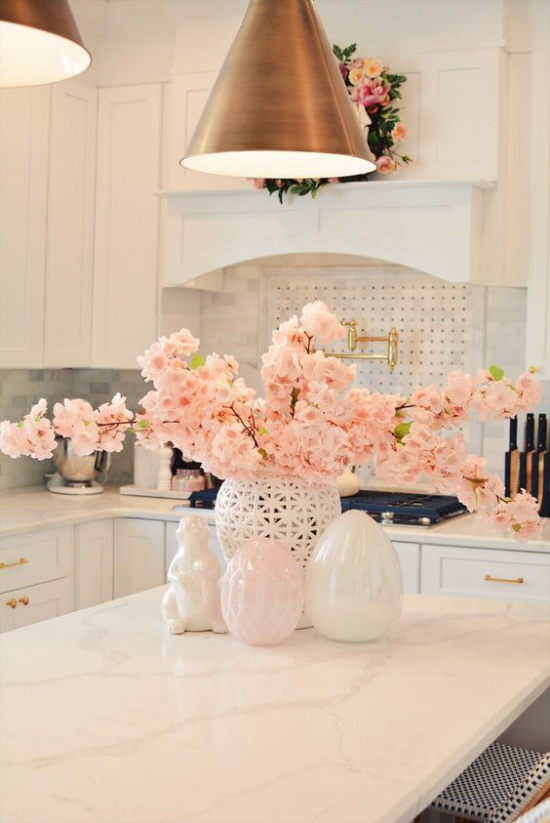 Frühlingshafte Tischdeko blühende Kirschzweige in Zartrosa eyecatching auf der weißen Marmorplatte in der Küche