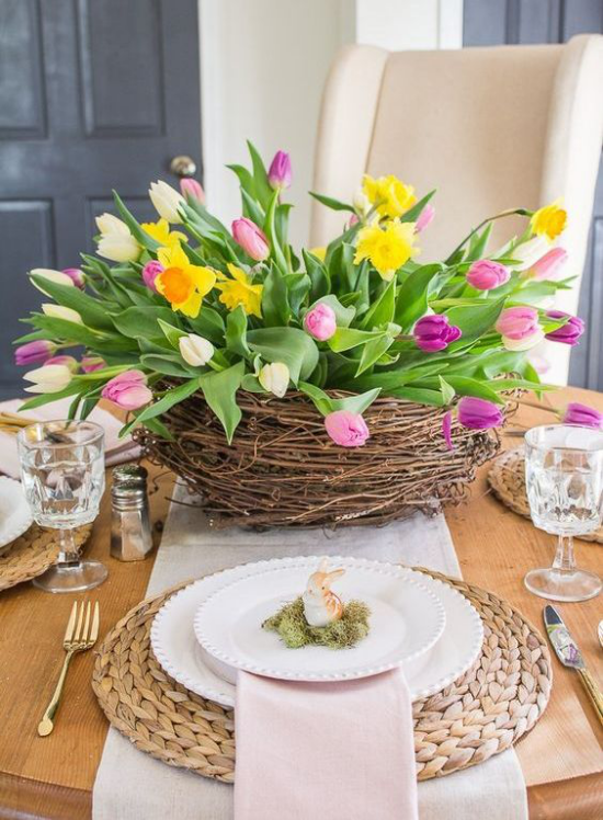 Frühlingshafte Tischdeko richtiger Blickfang farbenfrohe Tulpen Osternest aus Weidenzweigen festlich gedeckter Tisch