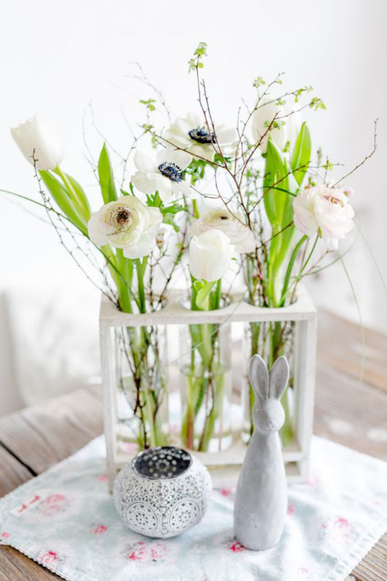 Frühlingshafte Tischdeko schöne weiße Frühlingsblüten Glasgefäß ein Hase vorne Osterfigur