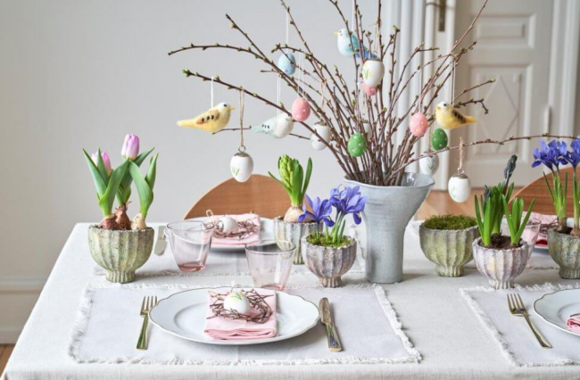 Osterstrauch schmücken farbenfrohe Osterdeko festlich dekorierter Tisch Vase Blumentöpfe Eier nestert Vögel hängen