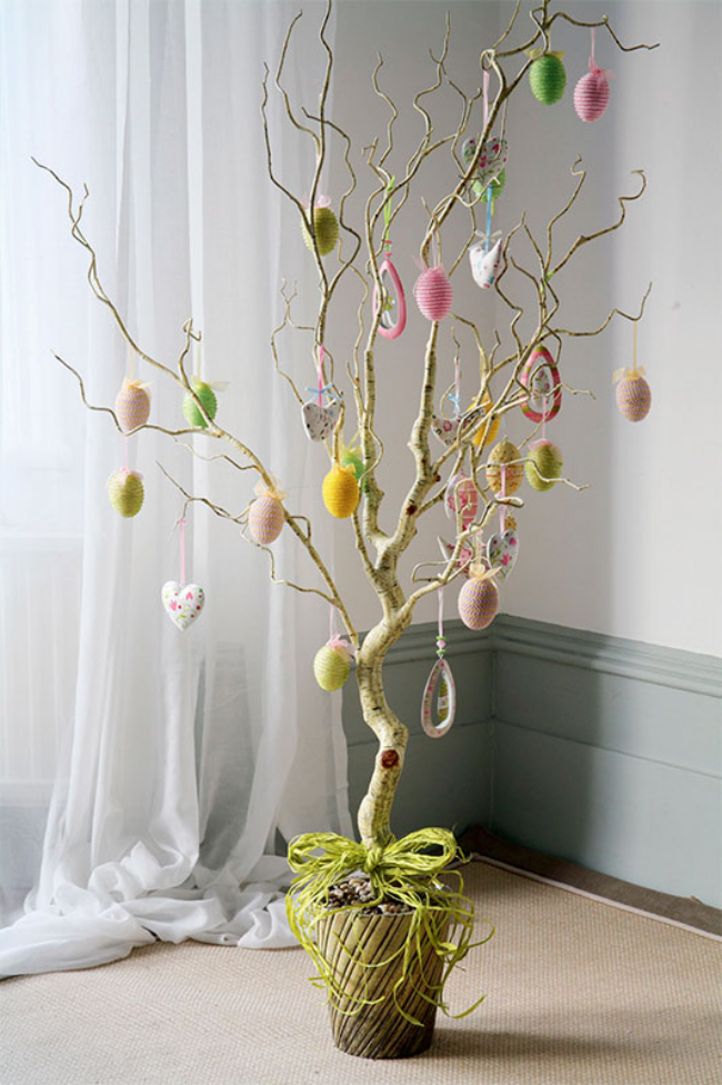 Osterstrauch schmücken kahle Zweige im Blumentopf drinnen neben dem Fenster prächtig verziert bunt bemalte Eier schöne Osterdeko