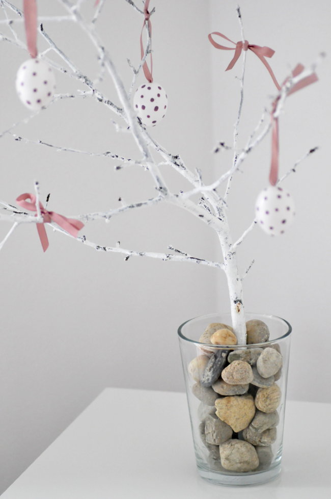 Osterstrauch schmücken minimalistisch gestaltet Glasgefäß mit kleinen Flusssteinen gefüllt Birkenzweige weiße Eier rosa Schleife