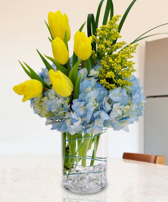 Schöne Blumenarrangements Vase aus Glas zitronengelbe Tulpen hellblaue Hortensien Farbkontrast