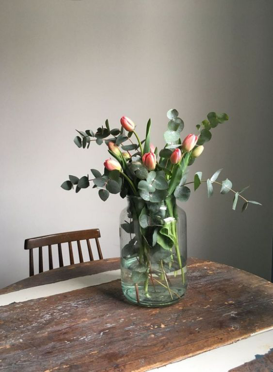 Schöne Blumenarrangements Vintage Tisch Tulpen grüne Blätter im Glas