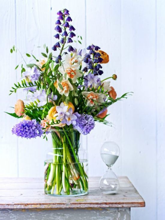 Schöne Blumenarrangements verschiedene Frühlingsblumen ein farbenfrohes Blütenmeer im Glasgefäß Blickfang auf einem alten Holztisch