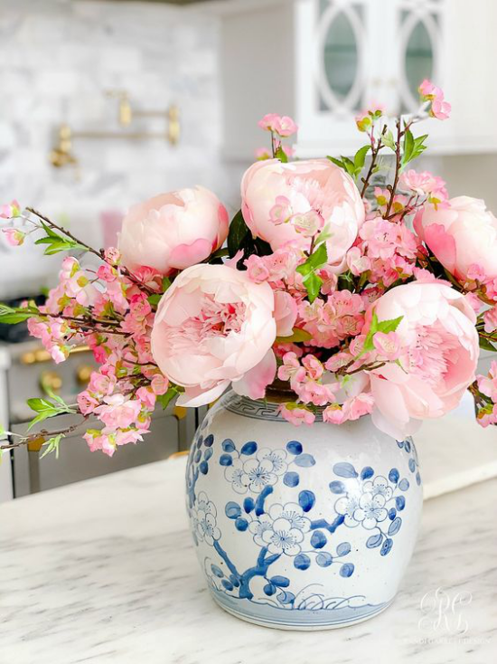 Schöne Blumenarrangements weiße Vase mit blauem Muster Päonien in zartem Rosa Kirschzweige mit ersten blühenden Knospen in Rosa
